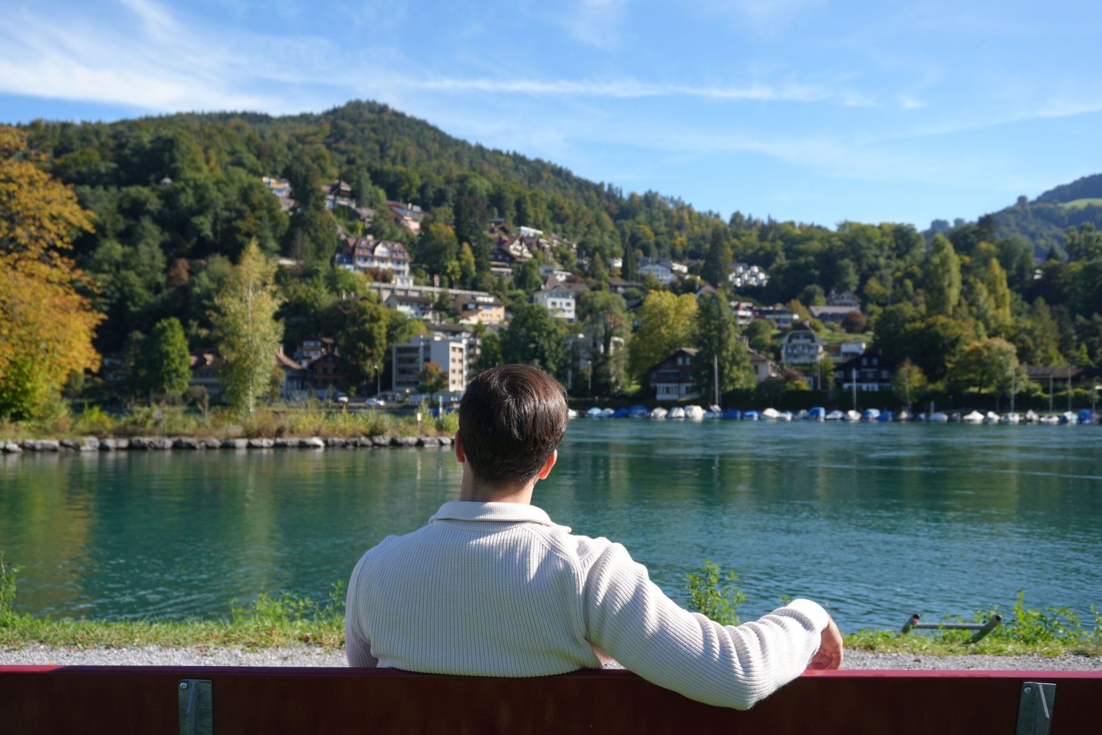 A man enjoys a peaceful view of the lake and mountains in Thun, Switzerland.